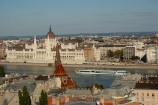 widok na czerwone dachówki Budy, monumentalny budynek parlamentu w Peszcie i barkę na Dunaju